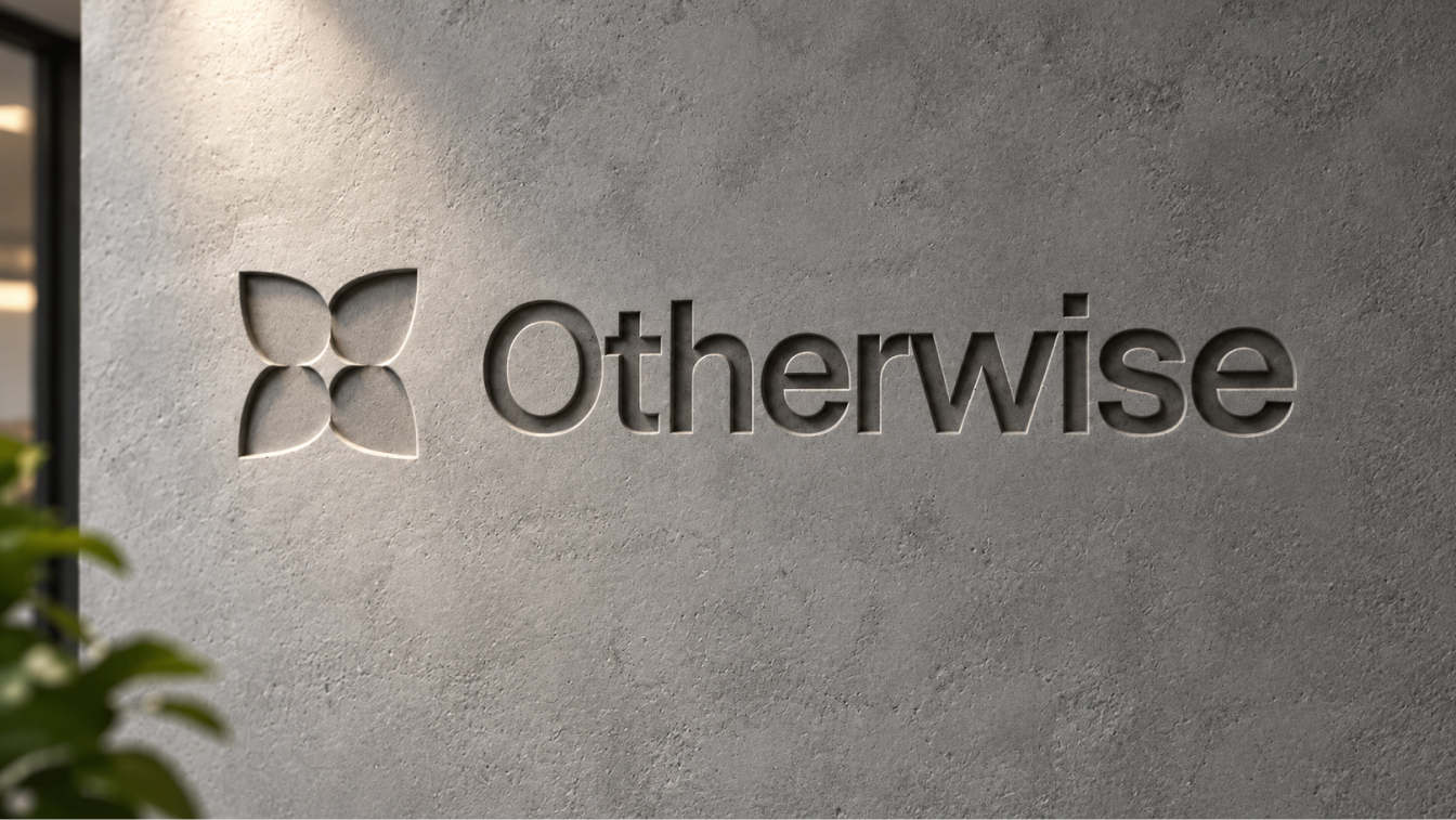 Otherwise symbol and wordmark embossed into a textured concrete wall, lit from the upper left